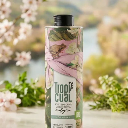 Tropicual de Vega Bio-Olivenöl in der 500ml Dose, präsentiert auf einem hellen Steintisch vor einem weichgezeichneten Hintergrund mit blühenden Mandelbäumen und mediterraner Landschaft.