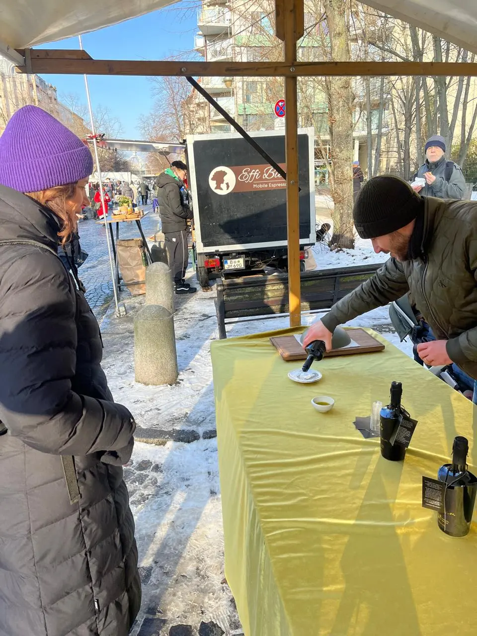 Dimitri Baitinger schenkt einer Kundin am Marktstand am Winterfeldtplatz in Berlin ein Glas „Aviv