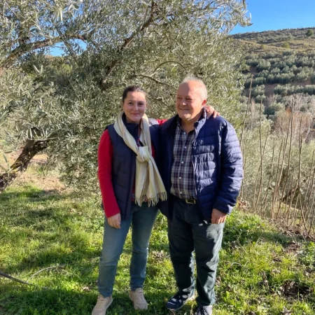 Die Olivenbauern-Familie hinter Avivoil vor einem ihrer Olivenbäume mit Blick auf die andalusischen Hügel